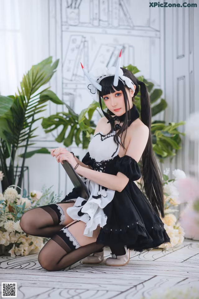 A woman in a black and white dress sitting on the floor.