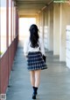 A woman in a school uniform walking down a hallway.