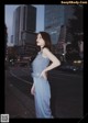 A woman in a blue dress standing on a city street.