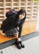 A young woman in a school uniform crouching on the floor.