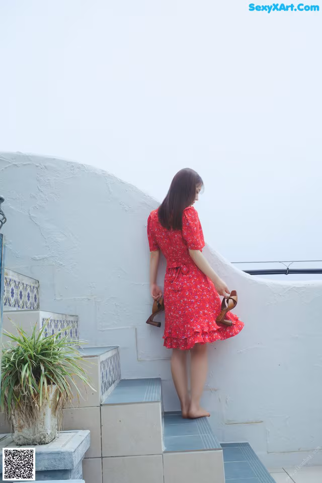 A woman in a red dress is standing on some steps.