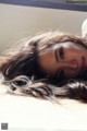 A woman laying on a bed with her hair blowing in the wind.