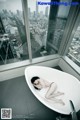 A woman laying in a bathtub in front of a window.