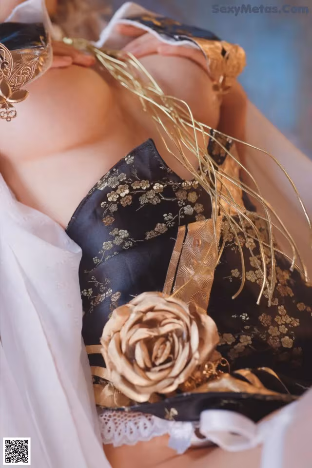 A woman in a black and gold lingerie with a rose on her chest.