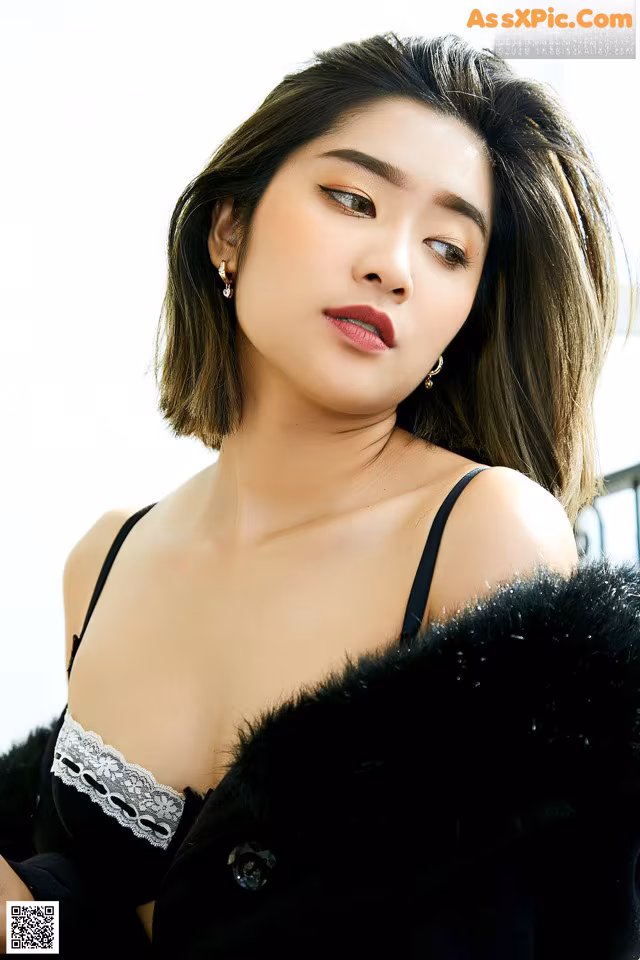 A woman in a black dress and fur coat posing for a picture.