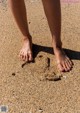 A person standing on a sandy beach with their feet in the sand.