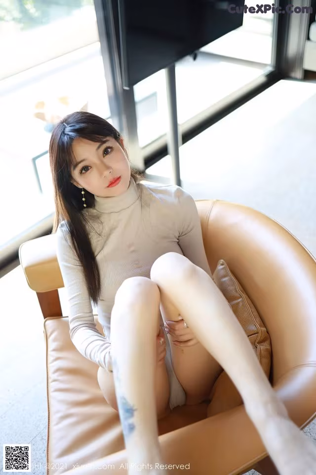 a woman sitting on top of a chair next to a window