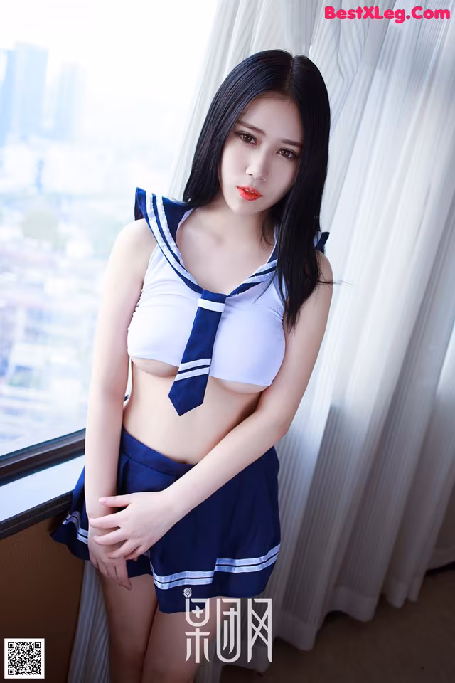 A woman in a sailor outfit posing by a window.