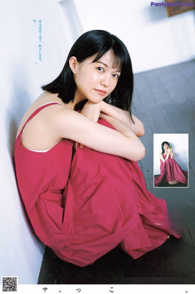A woman in a pink dress leaning against a wall.