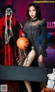 A woman dressed as a witch and a skeleton holding a pumpkin.