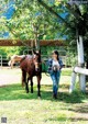 A woman walking a horse in a fenced in area.