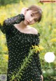 A woman in a black dress standing in a field of yellow flowers.