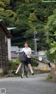 A woman riding a bike down a street next to a building.