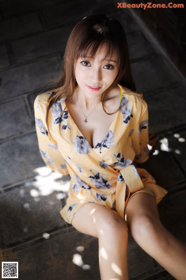 A woman in a yellow dress sitting on the ground.