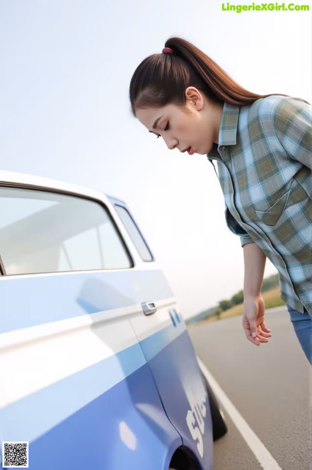 A woman leaning on the side of a blue and white car.