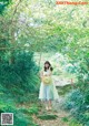 A woman in a green dress and straw hat walking down a path.