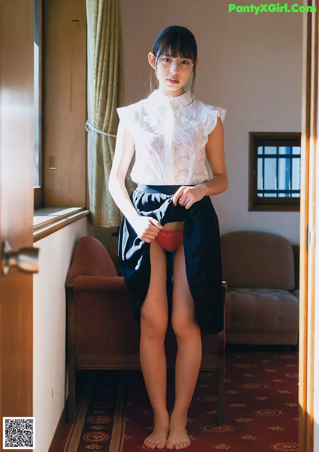 A woman in a white shirt and black skirt standing in a room.
