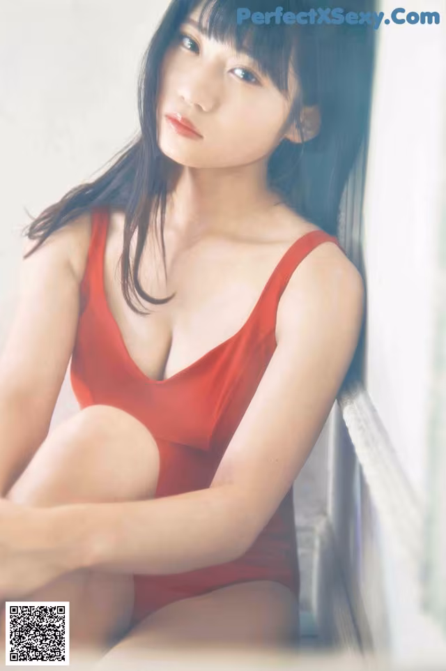 A woman in a red bathing suit sitting on a window sill.