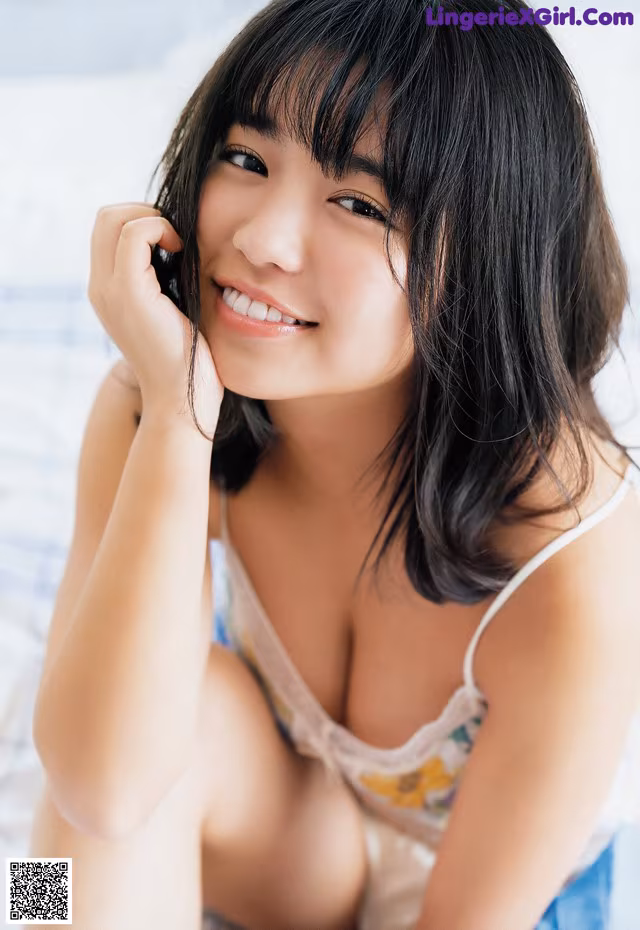 A woman sitting on a bed smiling at the camera.