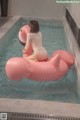 A woman in a white bathing suit sitting on an inflatable flamingo.