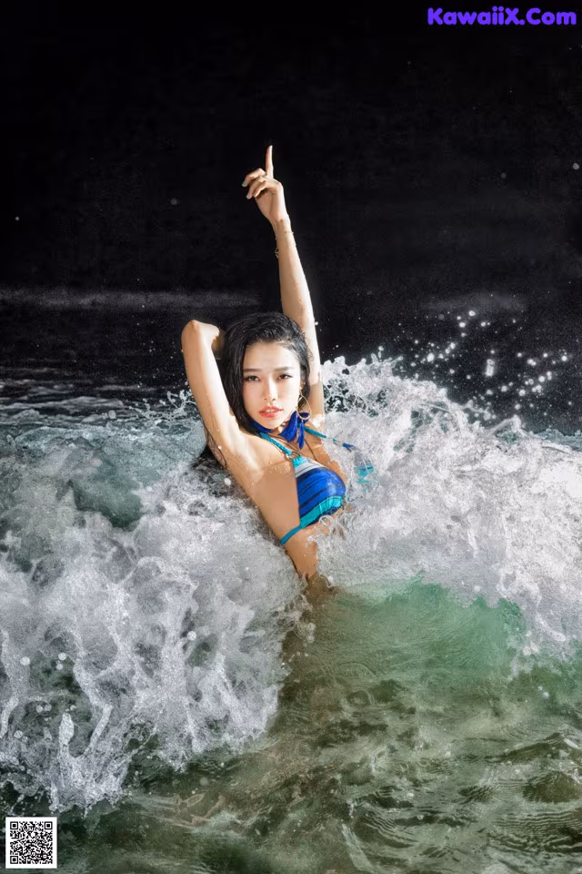 A woman in a blue bikini is in the water.