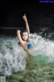 A woman in a blue bikini is in the water.