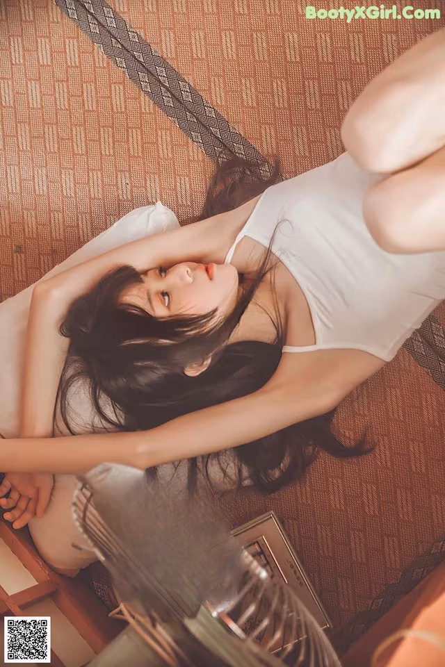 A woman laying on the floor next to a fan.